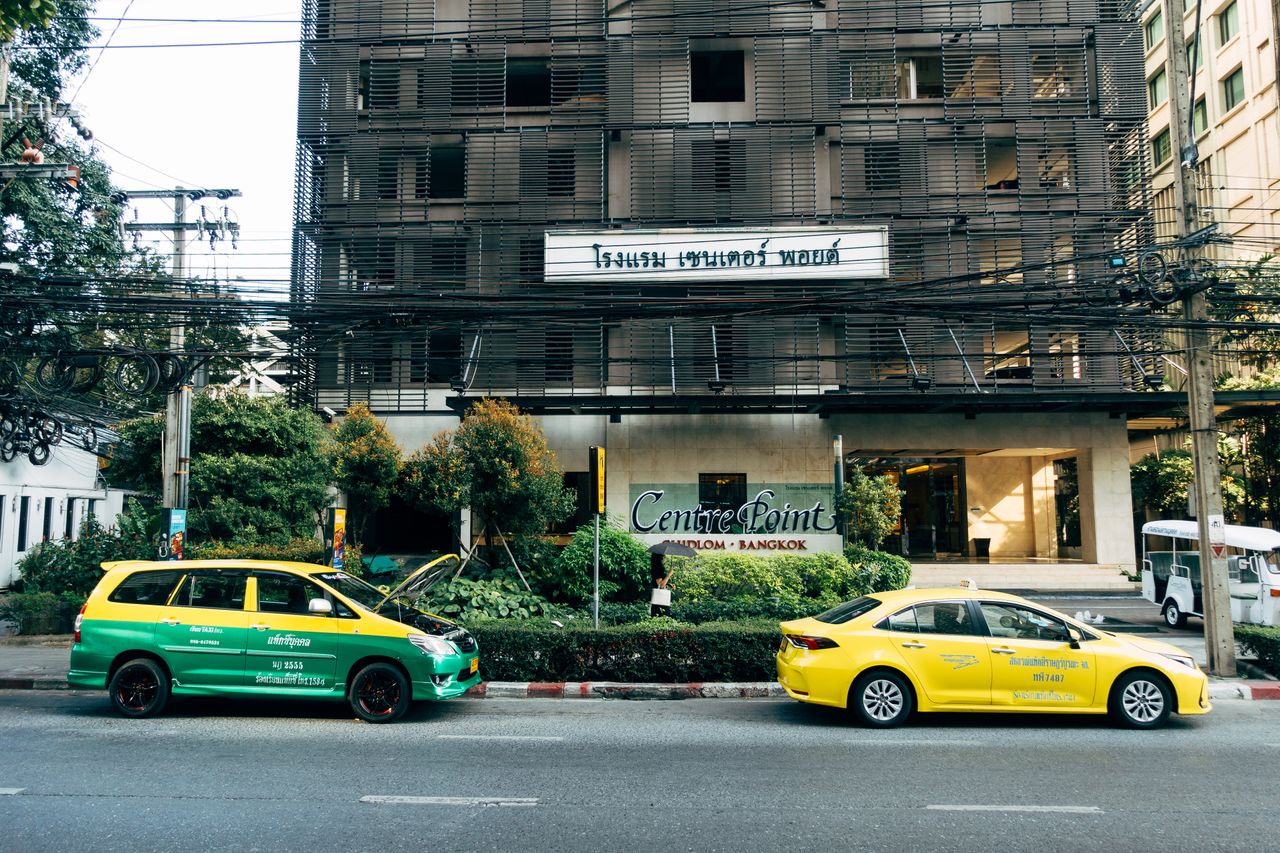 Home Colorful taxis parked outside Centre Point Hotel in Bangkok, showcasing urban transportation.