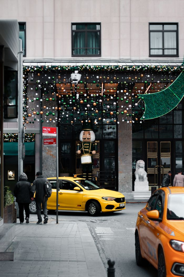 Urban street scene featuring Christmas decorations with yellow taxis and pedestrians in a lively city setting.