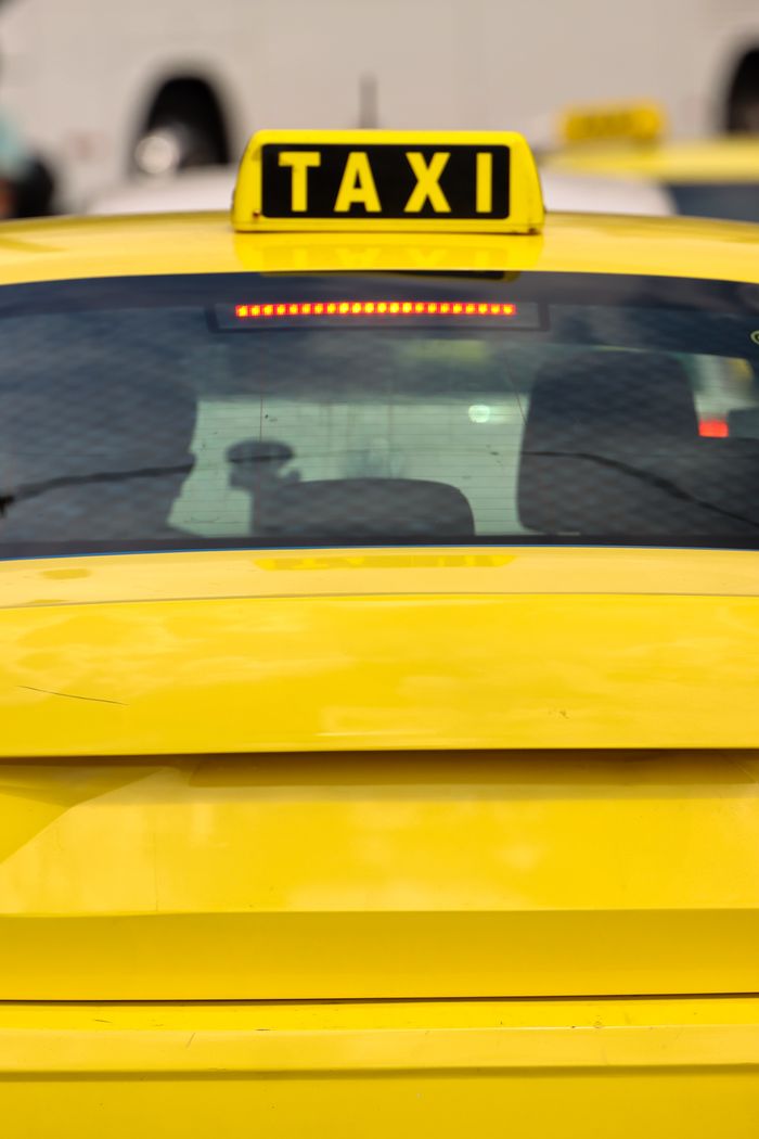 Close-up of a yellow taxi in Athens, Greece, highlighting the bright sign and urban setting.