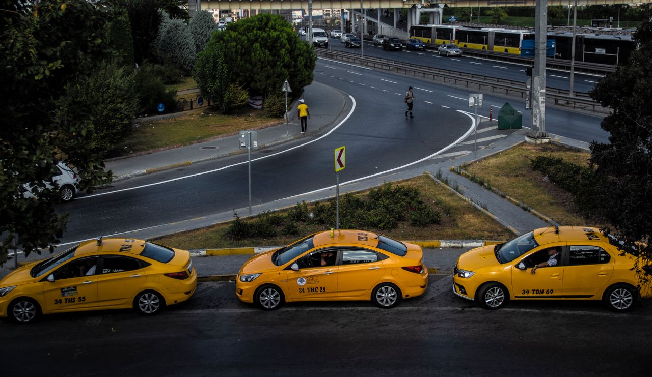 Aerial view of a city street with three yellow taxis and pedestrians crossing.