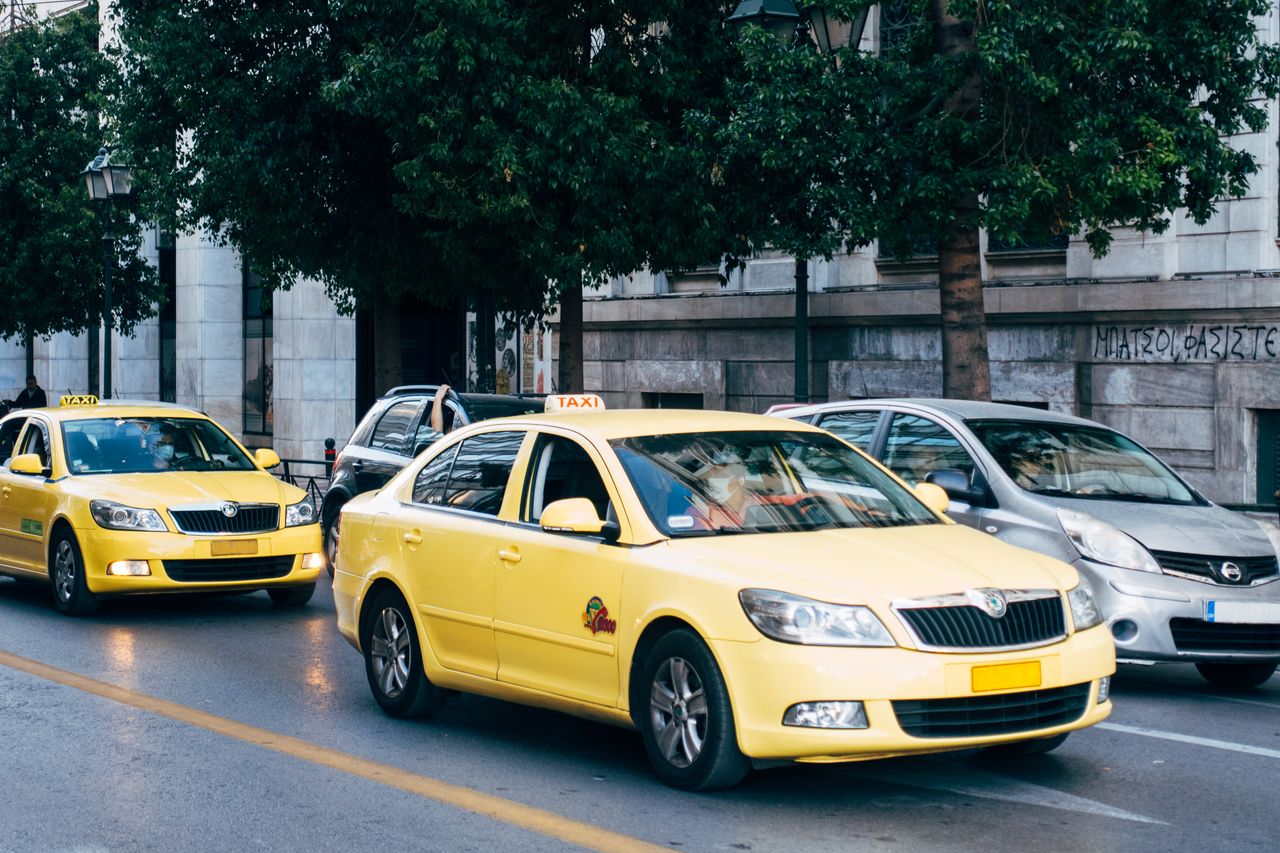 Home Yellow taxis lining the street in Athens, Greece, showcasing city's bustling transportation.